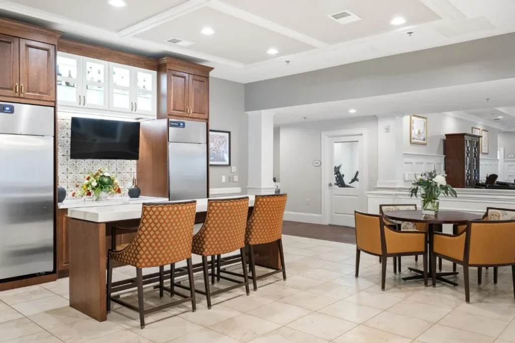 Kitchen with a marble island, brown bar stools, stainless steel appliances and a wall-mounted TV