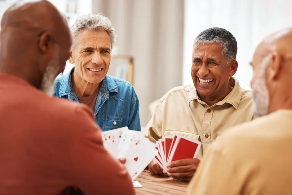 Group of older men laughing while playing cards at a table
