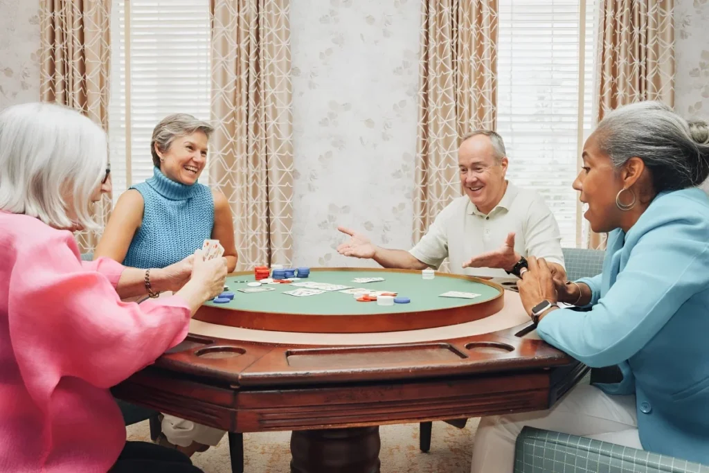Older adults playing cards around a round game table with poker chips
